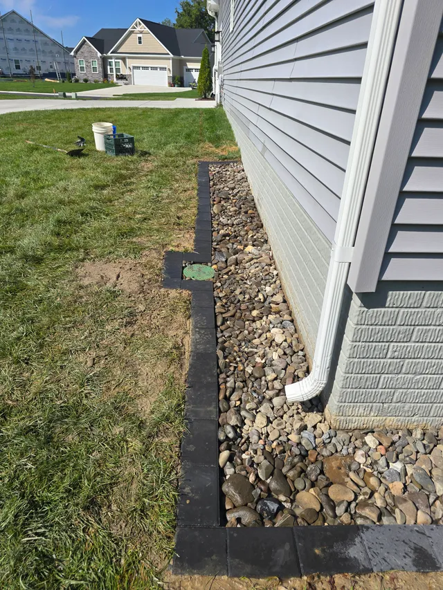 Downspout pipe draining into a gravel drain trench