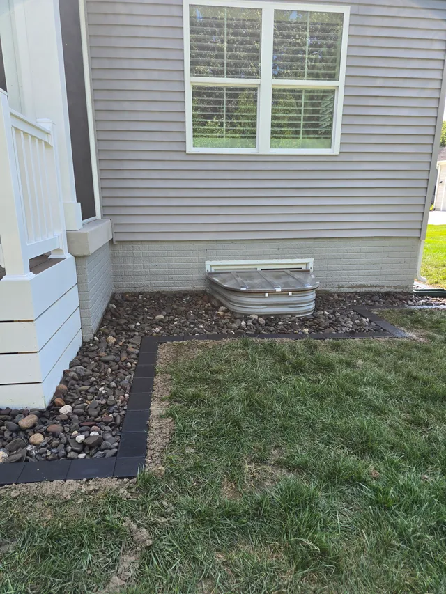 Egress window well with a rock drainage bed