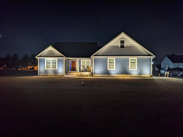Landscape lighting on a cape-style home at sunset