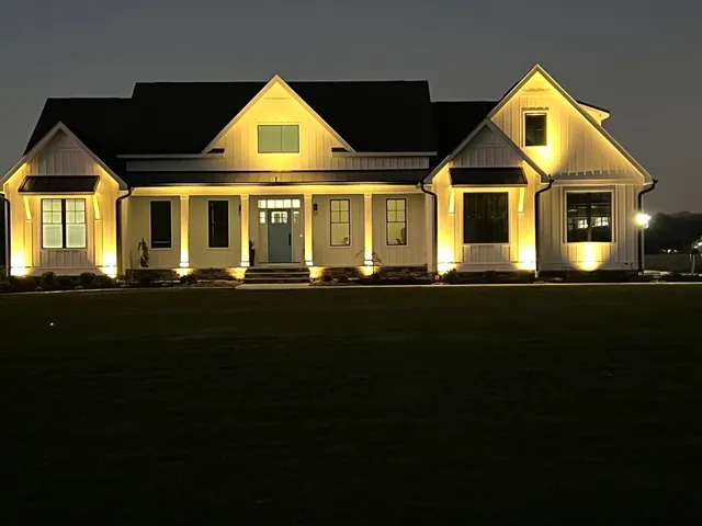 Landscape lighting installation on a farmhouse at night