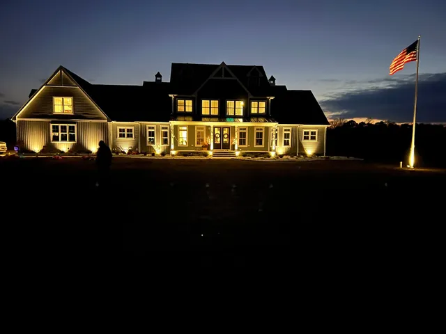 Landscape lighting highlighting a stone chimney at night