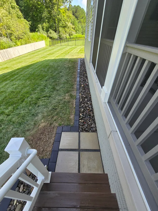 Paver patio and deck steps next to a drainage trench